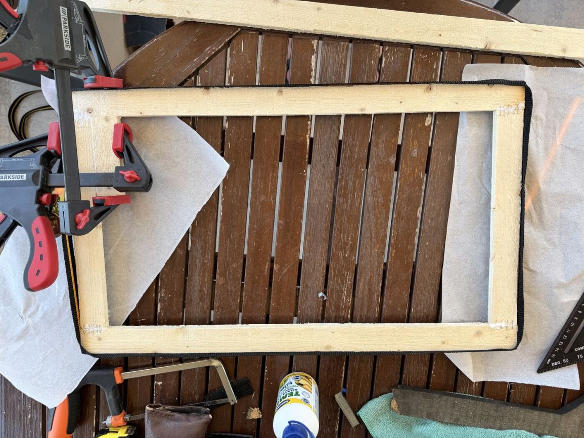 New wooden frame with the original cloth stapled and clamped in place